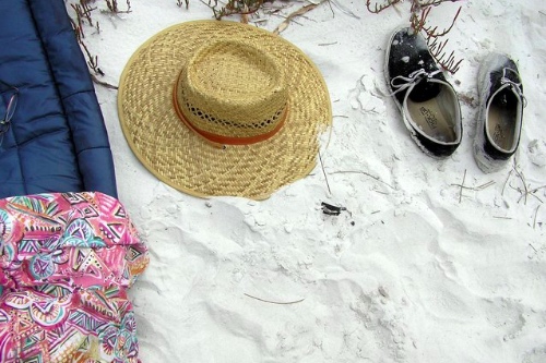 zonnehoed en schoenen in het zand om de rust van een vakantie in je eentje uit te beelden1jpg